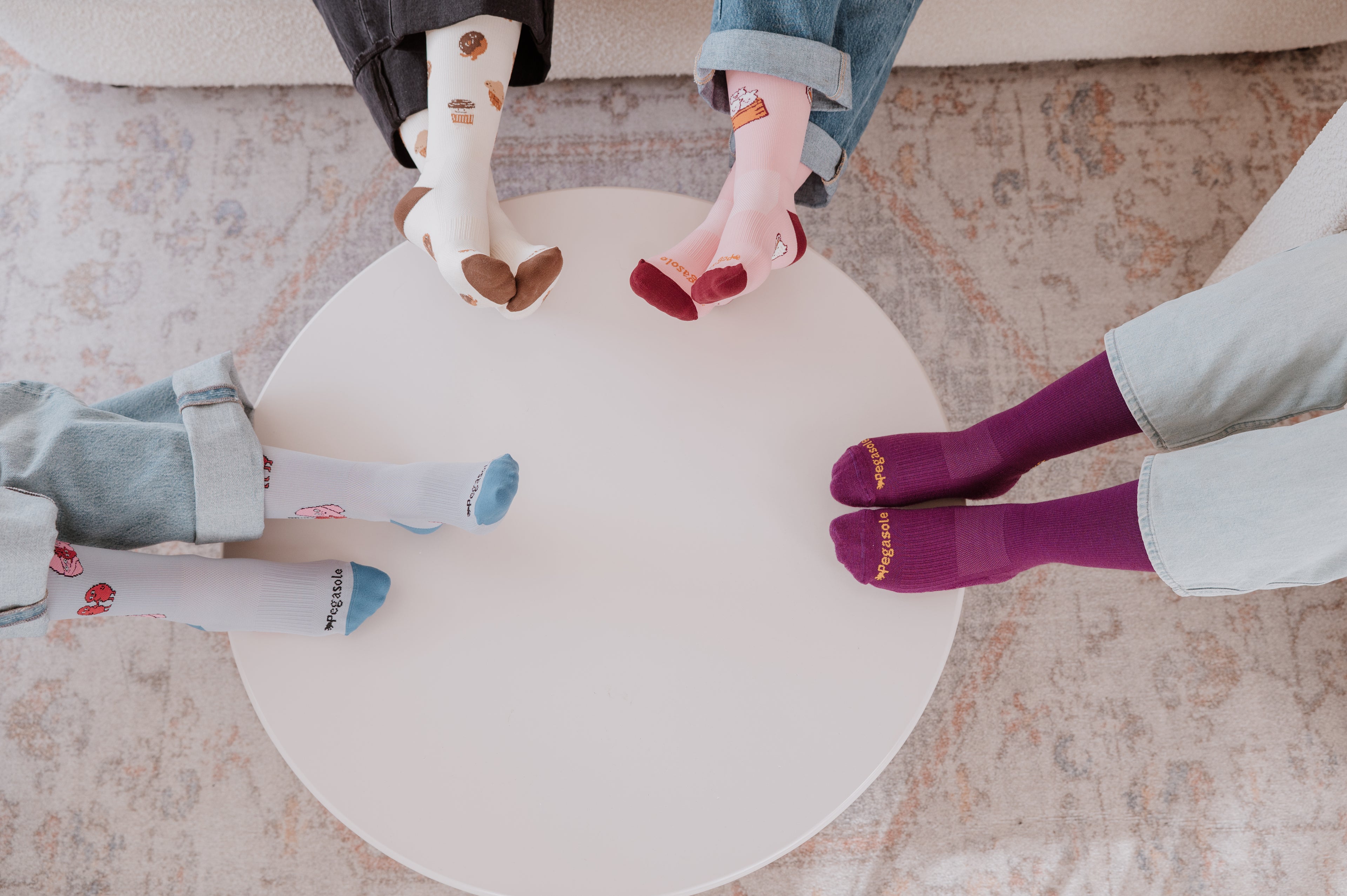 Four pairs of feet wearing Pegasole Compression socks on a round white table.