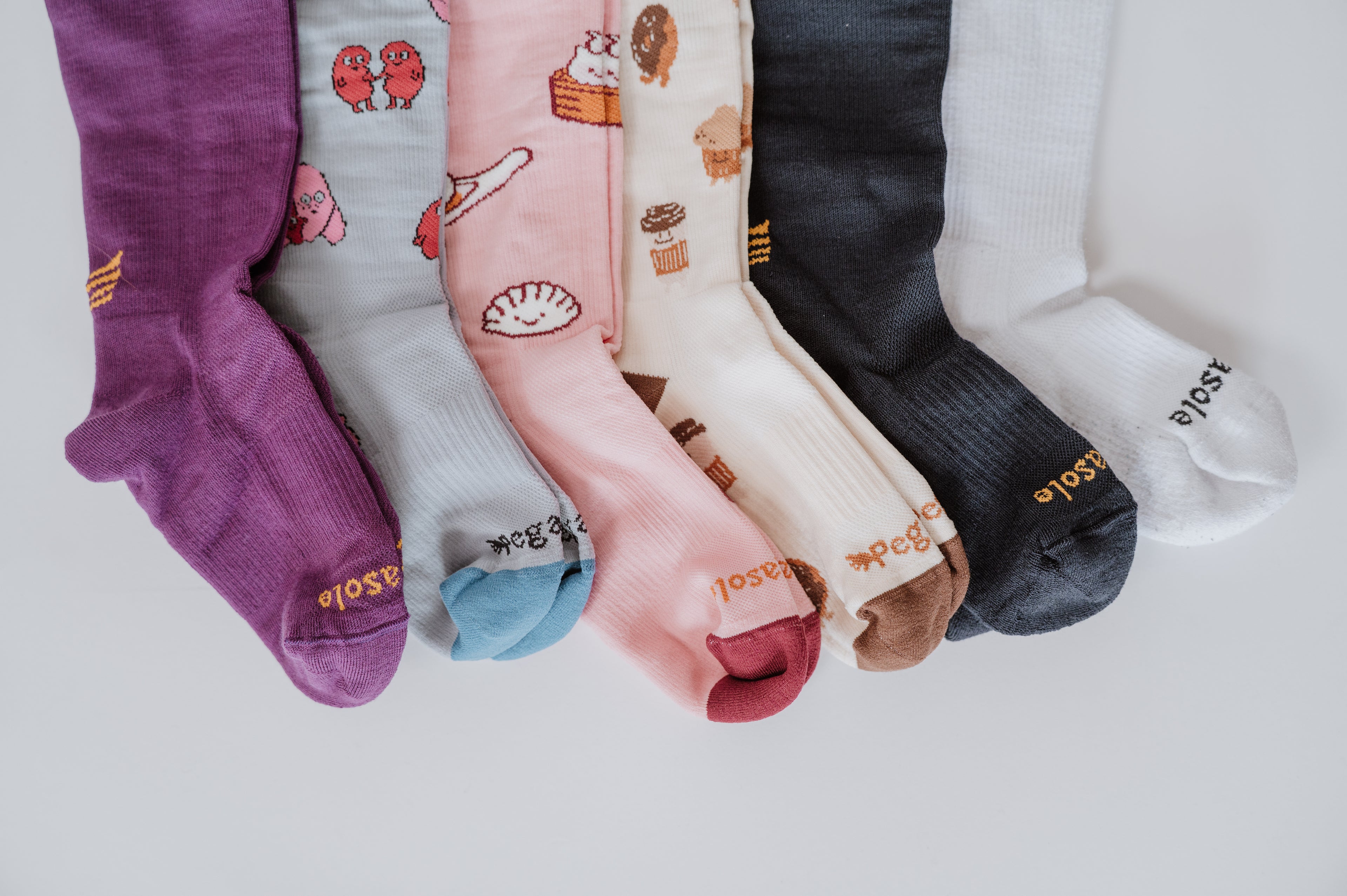 Set of colorful  Pegasole Compression socks with various patterns on a light gray background