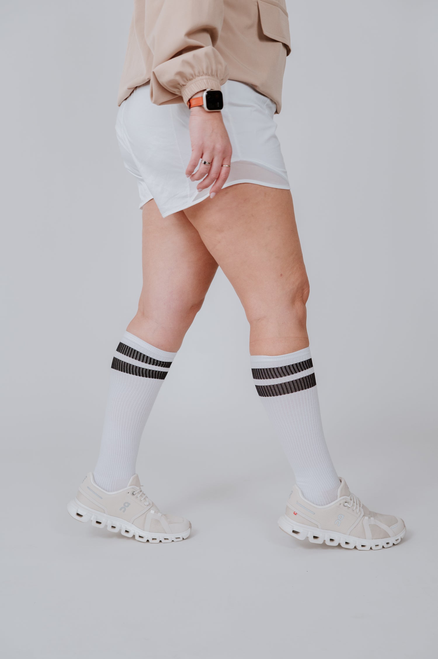 Person wearing white Pegasole Compression socks with black stripes on a plain background