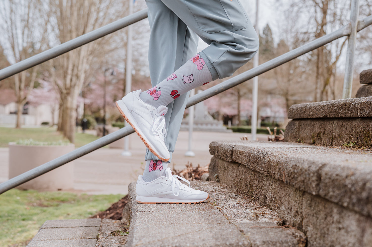 Person wearing light green pants and white sneakers with Pegasole Compression Socks walking up the steps outdoors.